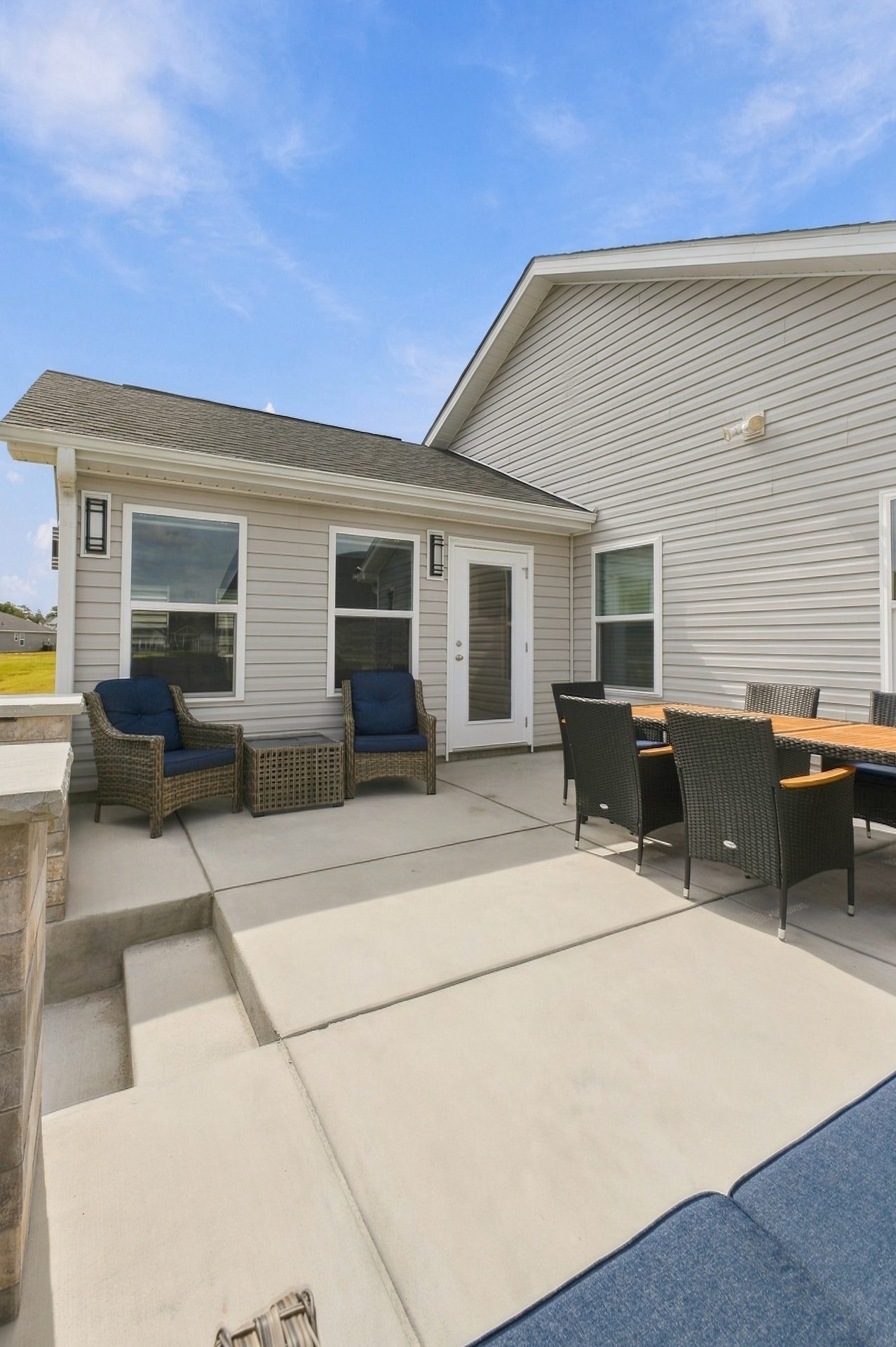 Patio and steps leading up to the sunroom door, with lounge seating and a dining set