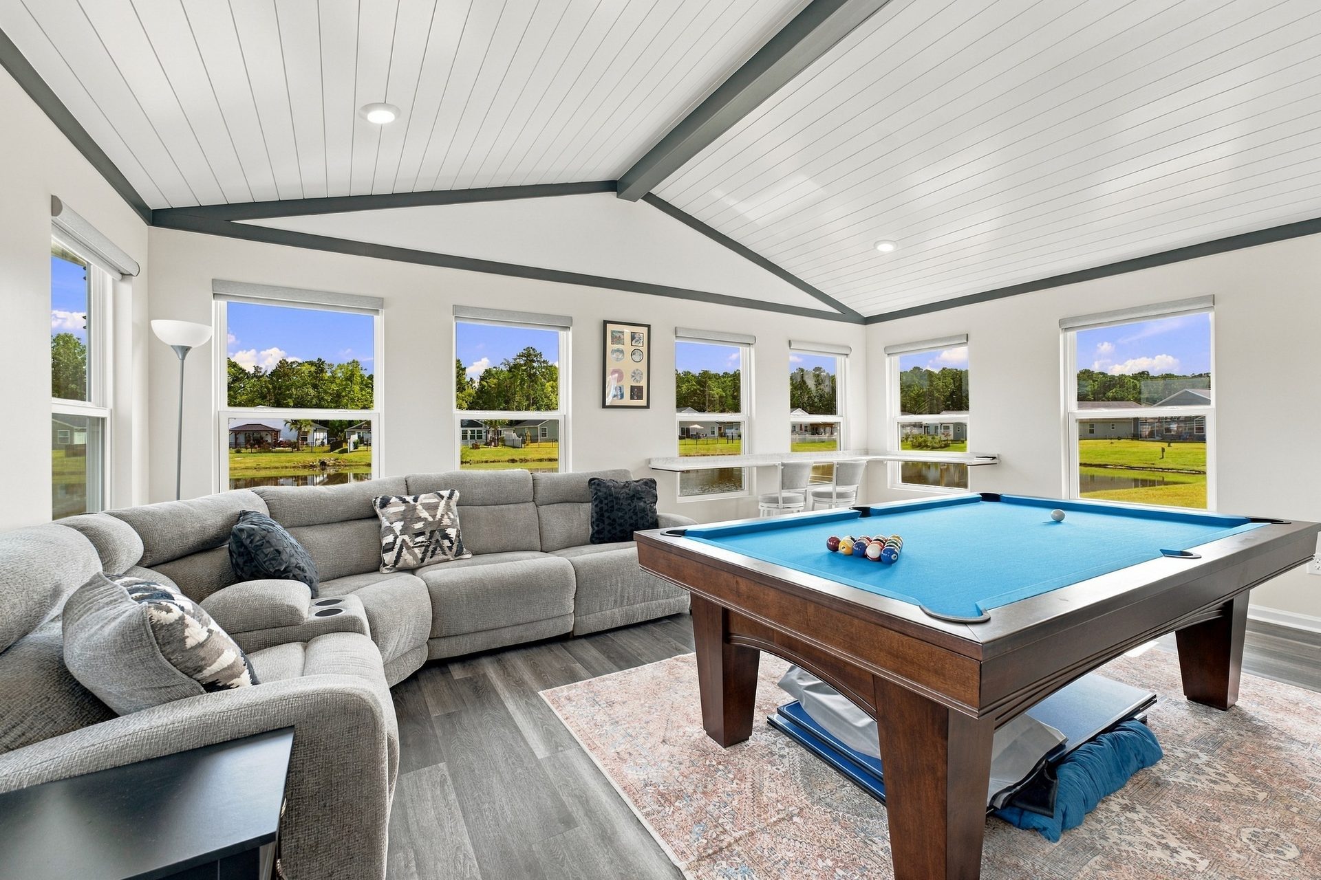 Sectional seating and a pool table in the sunroom addition, under the vaulted ceiling