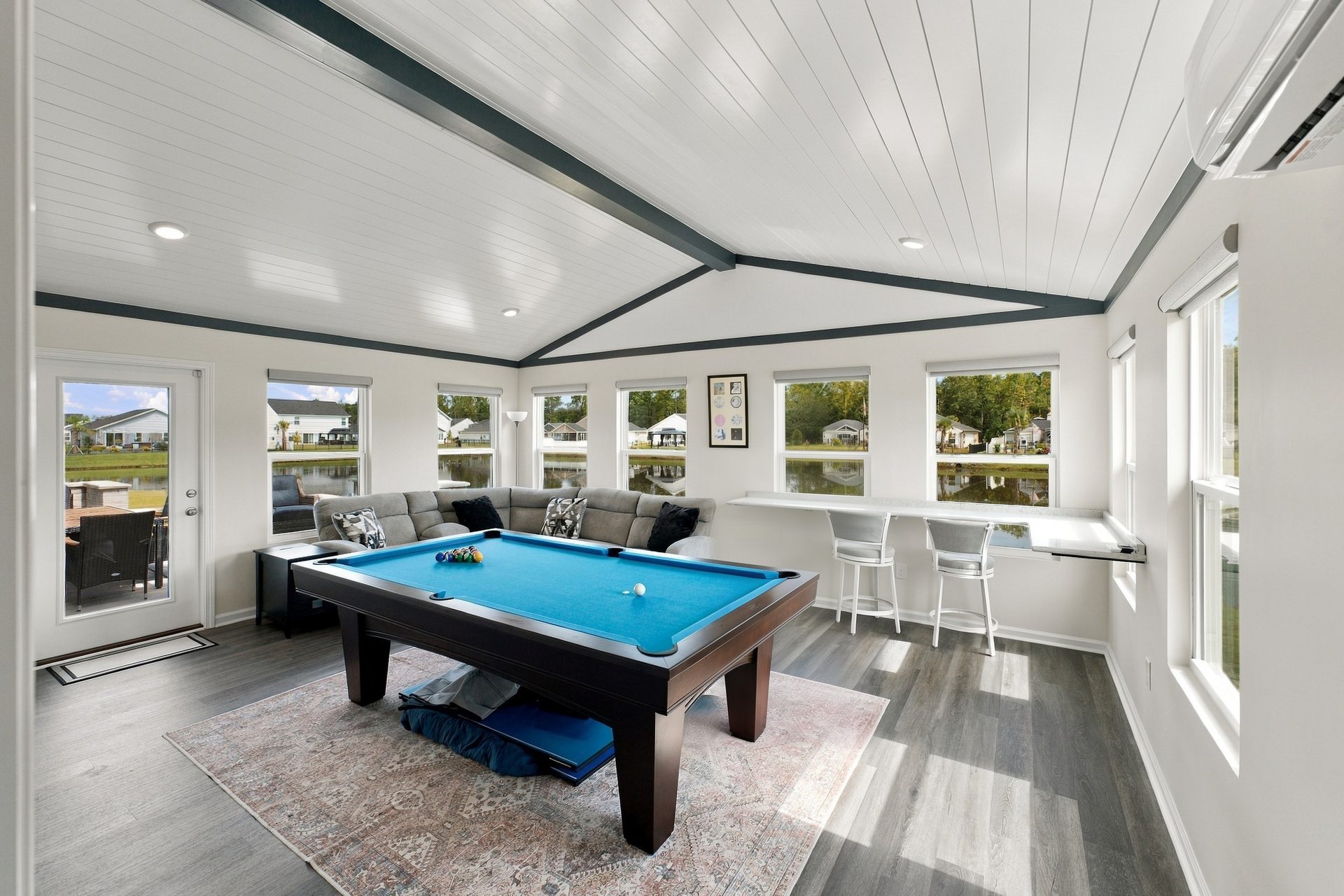 Interior of the sunroom addition with a vaulted tongue-and-groove ceiling, exposed painted beams and windows on three sides