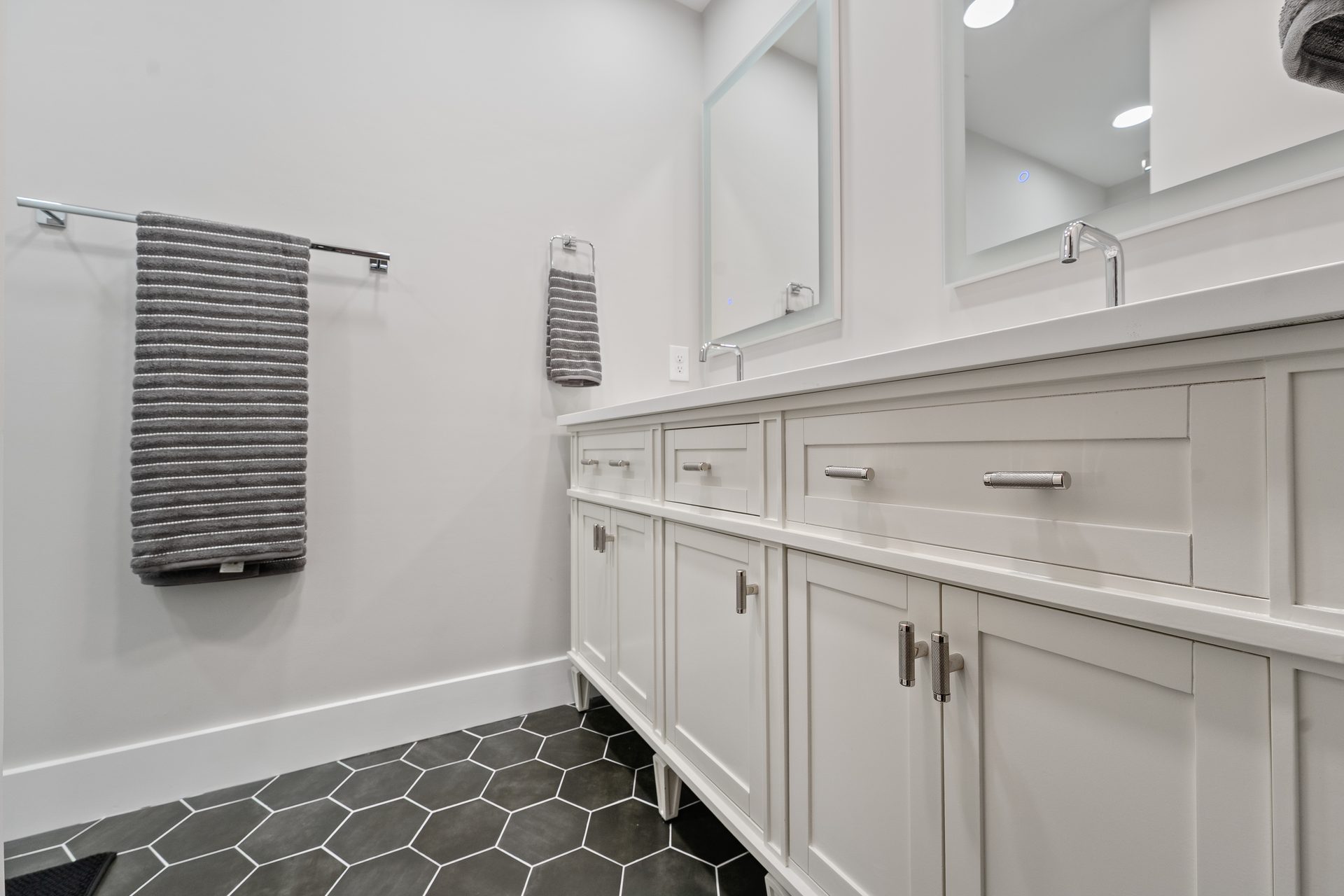 Renovated bathroom vanity run with quartz top and hexagon tile flooring