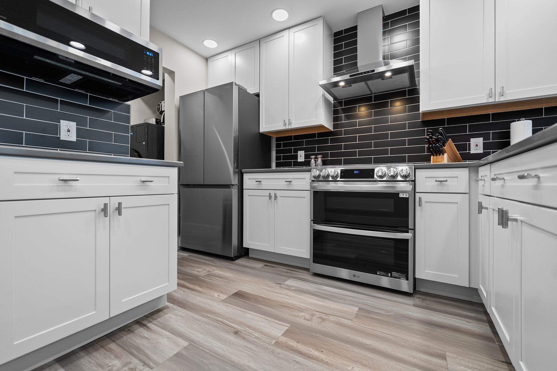 Renovated condo kitchen in North Myrtle Beach with white shaker cabinets, dark subway tile backsplash and stainless appliances