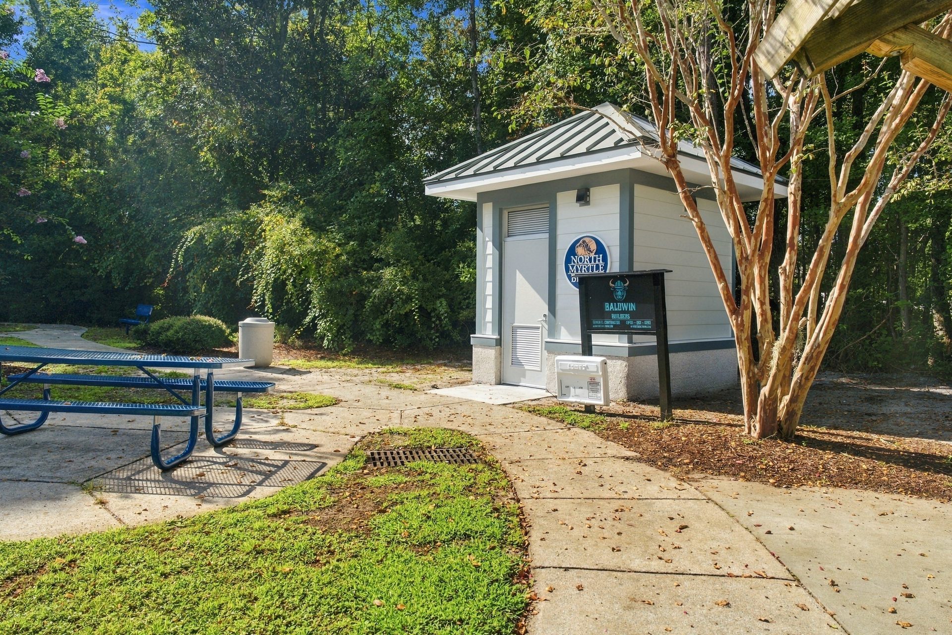 Restroom building at the junction of the park walkways, with picnic tables under the trees