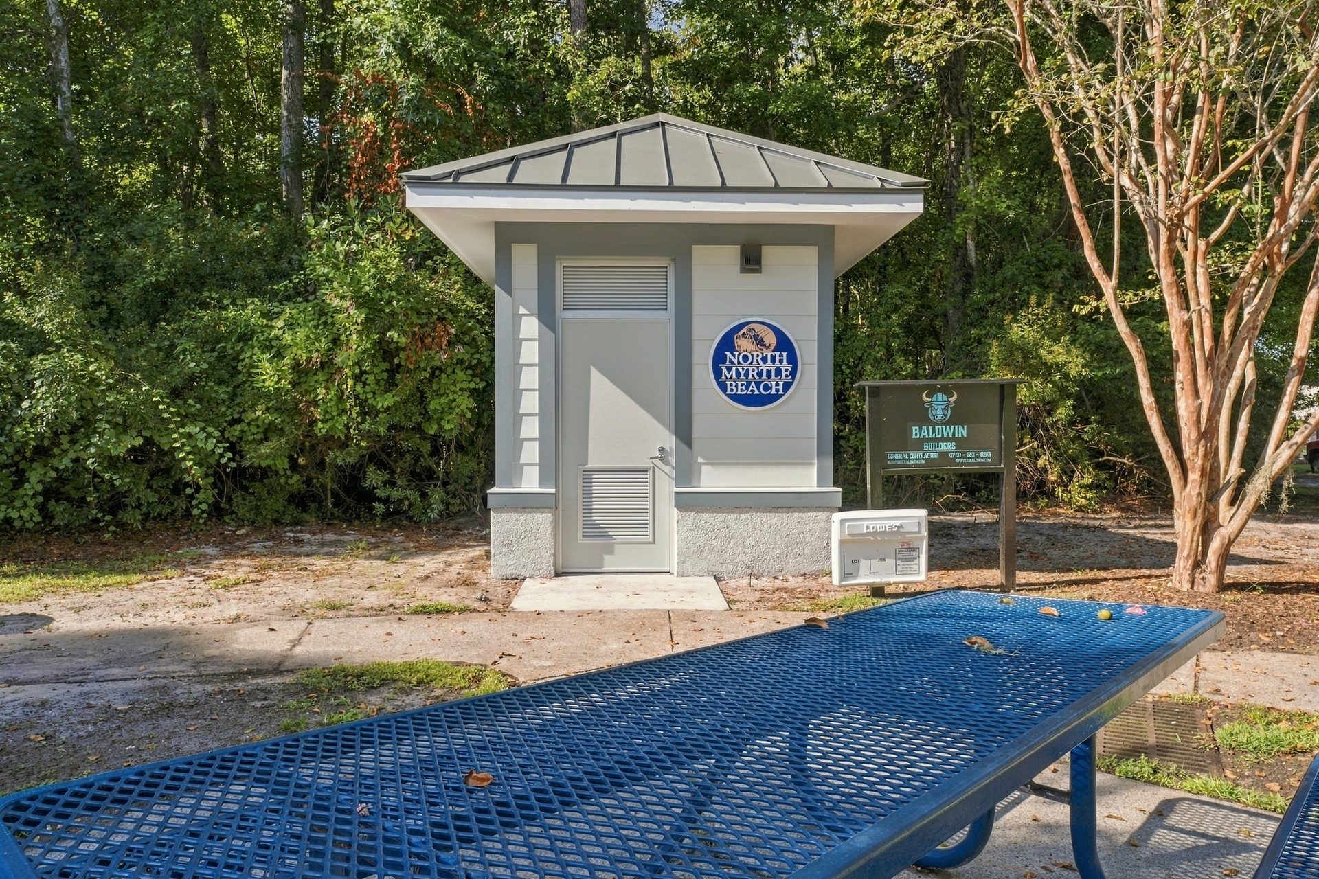 Restroom building beside the park picnic area, with a bench and waste receptacle on the concrete pad