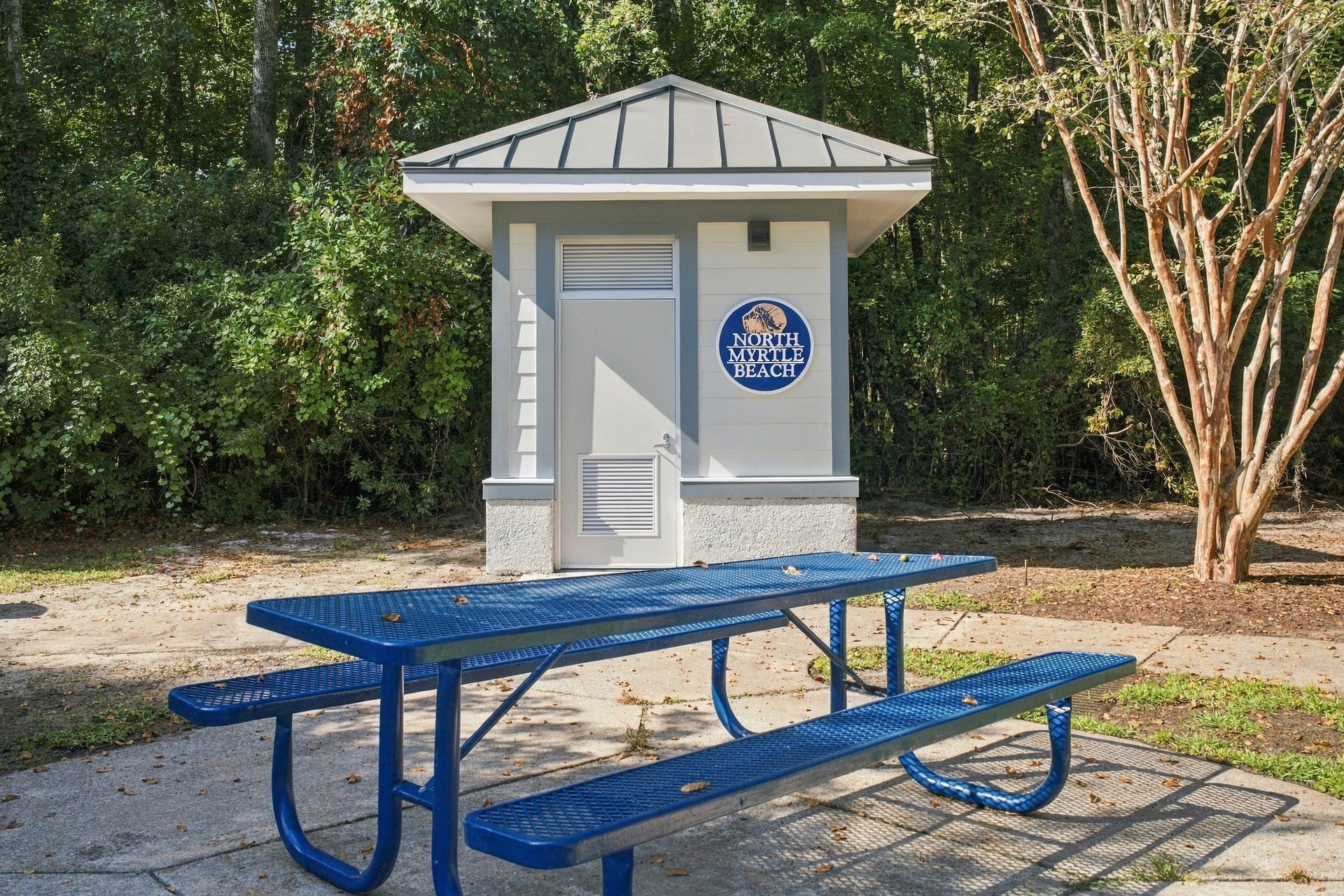 City restroom building with the City of North Myrtle Beach seal on the wall and a picnic table on the concrete pad in front